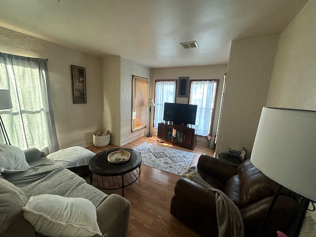 living area with wood finished floors, a textured wall, and baseboards