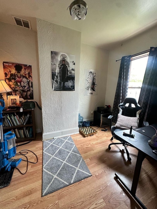 office space with a textured wall, wood finished floors, and baseboards