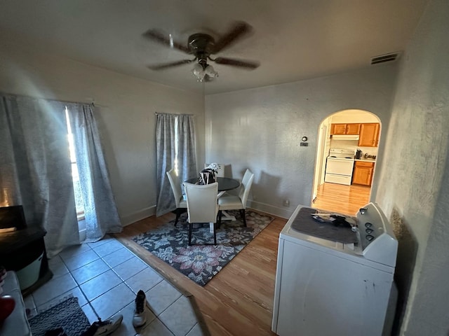dining room featuring washer / clothes dryer, arched walkways, a ceiling fan, and light wood-type flooring