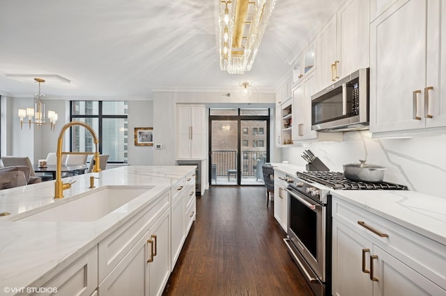 1122 N Dearborn St Unit 10A, Chicago, IL 60610 - kitchen featuring an inviting chandelier, a sink, white cabinets, appliances with stainless steel finishes, and ornamental molding