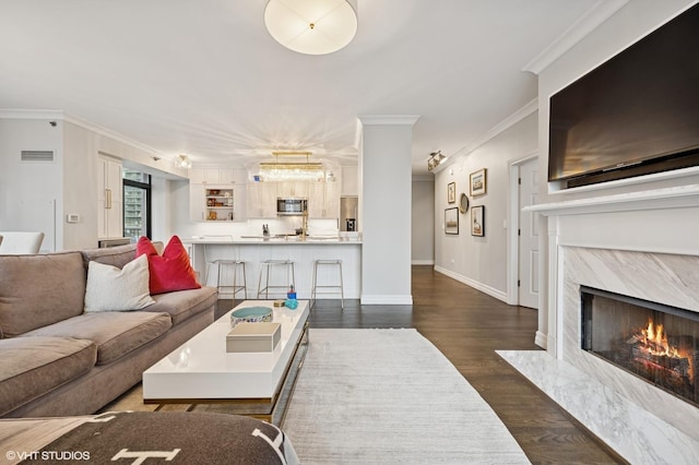 1122 N Dearborn St Unit 10A, Chicago, IL 60610 - living room featuring a premium fireplace, crown molding, visible vents, baseboards, and dark wood-style floors