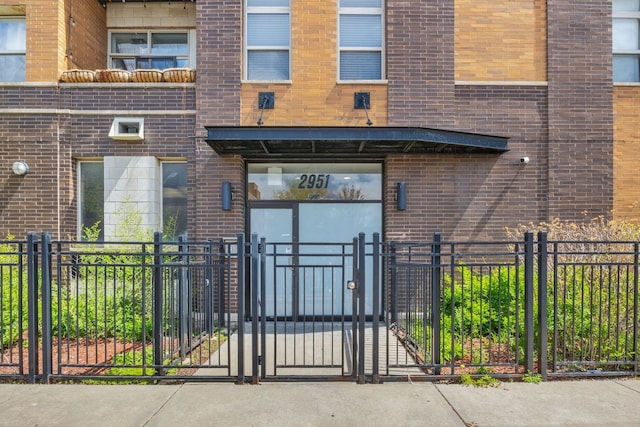 entrance to property with brick siding, a gate, and fence