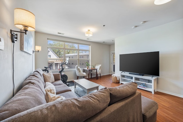 living room with baseboards, visible vents, and wood finished floors