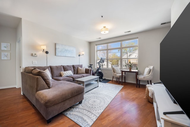 living room with baseboards, visible vents, and wood finished floors