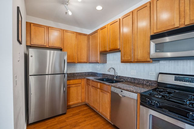 kitchen featuring a sink, stainless steel appliances, decorative backsplash, and dark wood finished floors