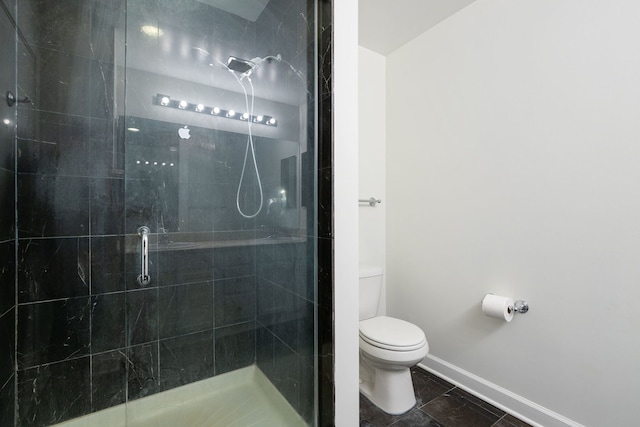 bathroom with toilet, a shower stall, and baseboards