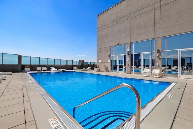 community pool with a patio area and fence