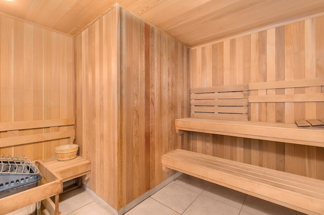 relaxing sauna with wood ceiling, tile patterned flooring, and wooden walls