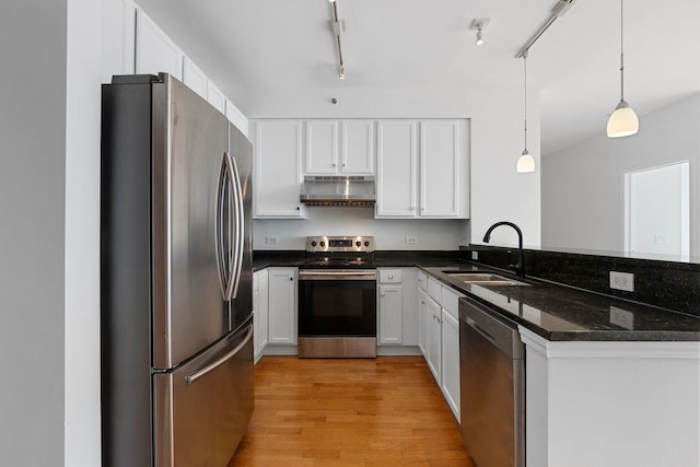 kitchen featuring appliances with stainless steel finishes, a sink, under cabinet range hood, a peninsula, and white cabinets