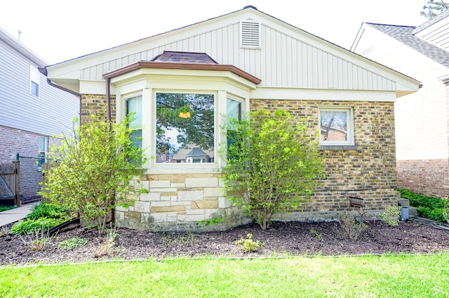 view of side of home featuring stone siding, brick siding, and fence