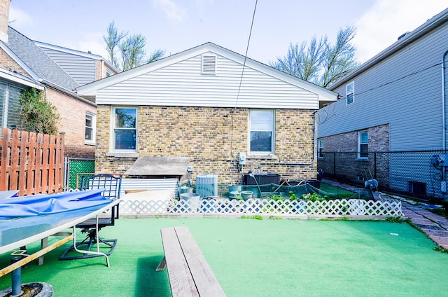 rear view of property with central air condition unit, brick siding, and a fenced backyard