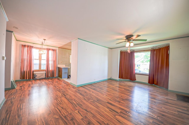 unfurnished living room featuring baseboards, ornamental molding, wood finished floors, and ceiling fan with notable chandelier