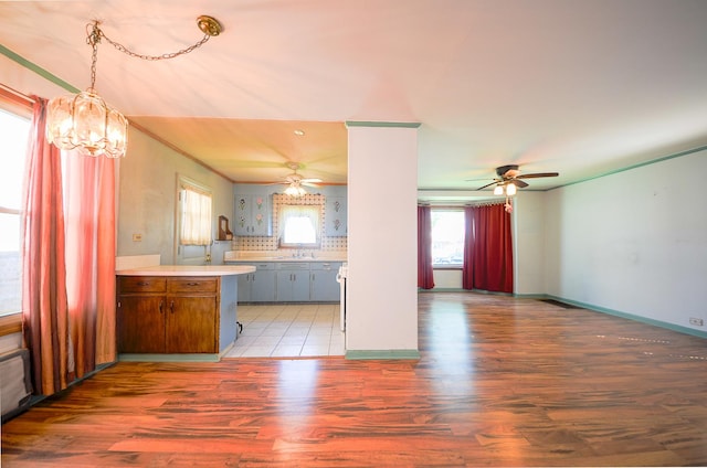 kitchen featuring a wealth of natural light, light countertops, light wood-style flooring, and ceiling fan with notable chandelier