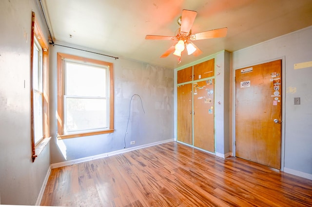 unfurnished bedroom featuring baseboards, a closet, ceiling fan, and wood finished floors