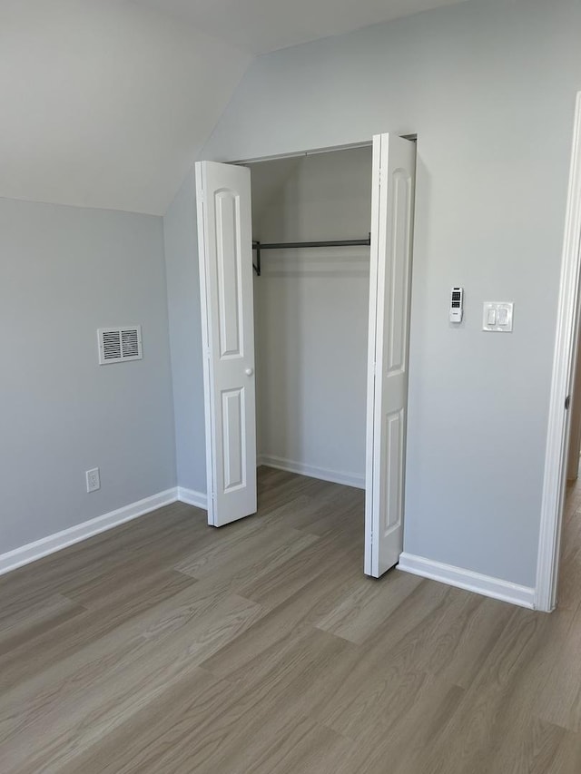 1122 N Mason Ave, Chicago, IL 60651 - unfurnished bedroom featuring wood finished floors, baseboards, vaulted ceiling, and a closet