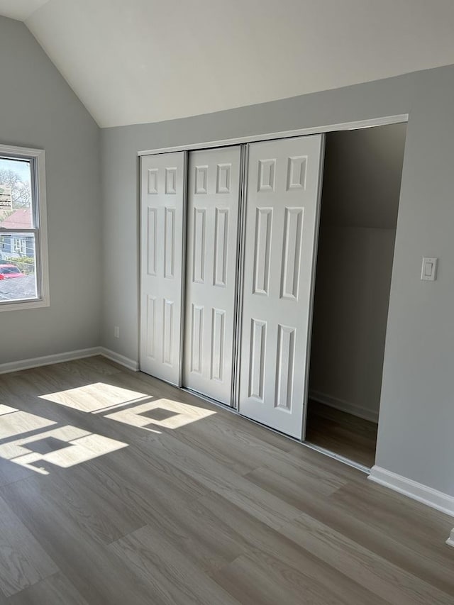 1122 N Mason Ave, Chicago, IL 60651 - unfurnished bedroom with wood finished floors, a closet, vaulted ceiling, and baseboards