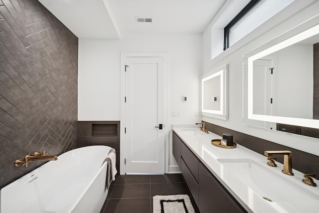full bath featuring a sink, tile walls, a freestanding bath, visible vents, and tile patterned flooring