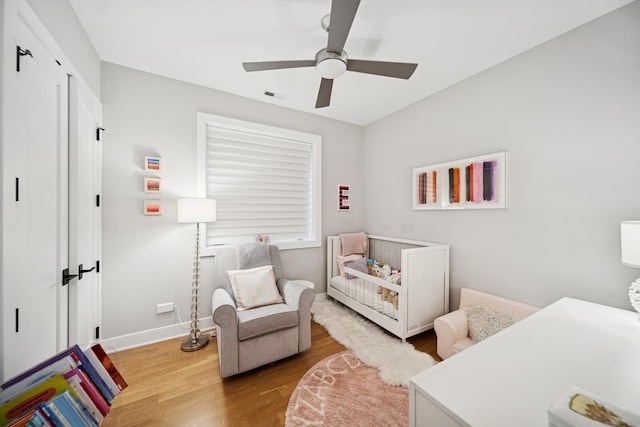 bedroom featuring ceiling fan, baseboards, visible vents, and wood finished floors