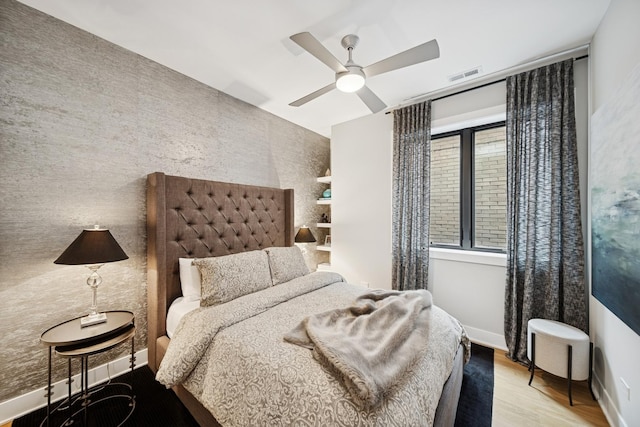 bedroom with baseboards, ceiling fan, visible vents, and wood finished floors