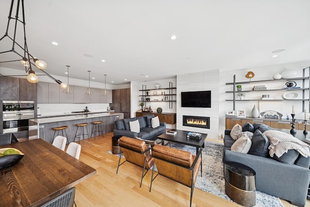 living room with light wood finished floors, a large fireplace, and recessed lighting