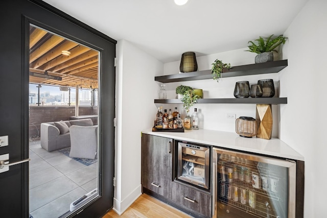 bar with wine cooler, a bar, and light wood-style flooring