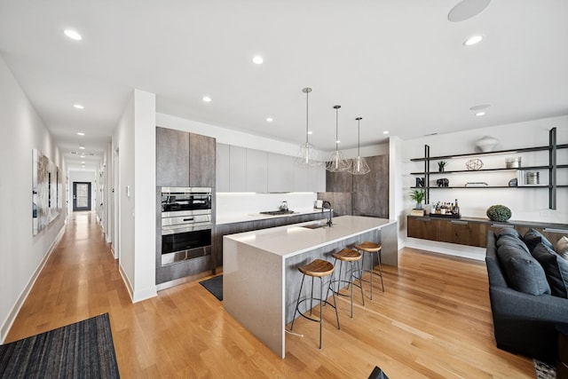 kitchen featuring a sink, a breakfast bar, modern cabinets, and light wood-style floors