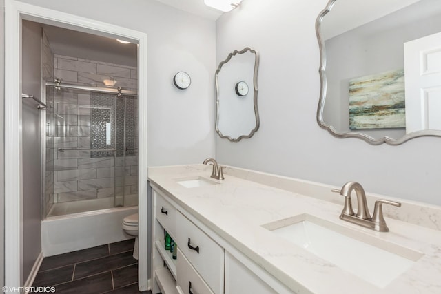 bathroom with toilet, double vanity, and bath / shower combo with glass door