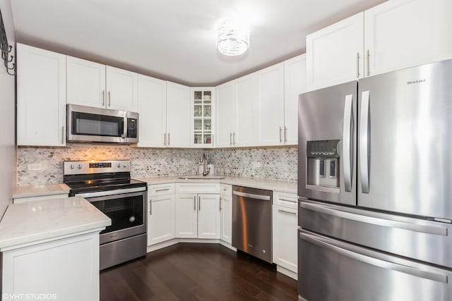 kitchen with appliances with stainless steel finishes, a sink, dark wood finished floors, and white cabinets