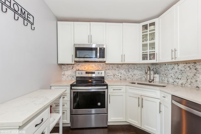kitchen featuring stainless steel appliances, a sink, light countertops, backsplash, and white cabinets