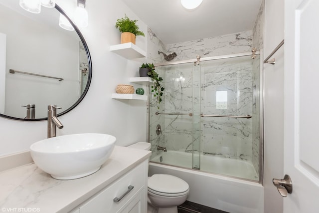 bathroom with bath / shower combo with glass door, toilet, and vanity