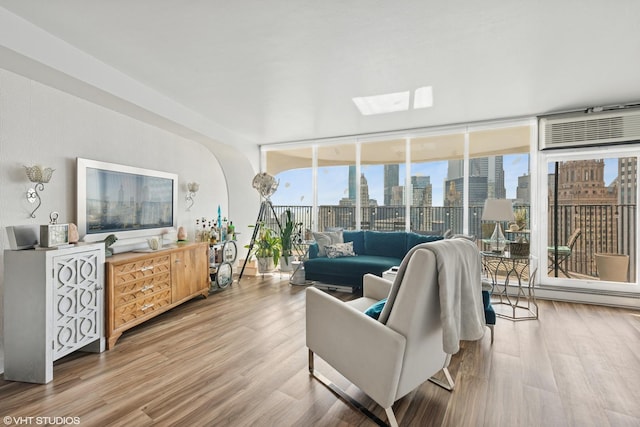 living area featuring arched walkways, floor to ceiling windows, wood finished floors, and healthy amount of natural light