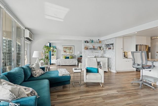 living room featuring wood finished floors, a wall mounted air conditioner, and bar