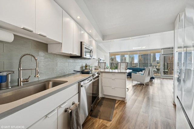 kitchen featuring a sink, appliances with stainless steel finishes, a peninsula, white cabinetry, and tasteful backsplash