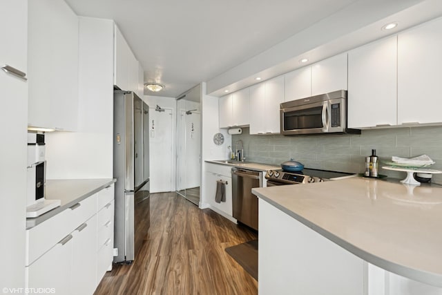 kitchen featuring appliances with stainless steel finishes, dark wood-style floors, tasteful backsplash, and white cabinetry