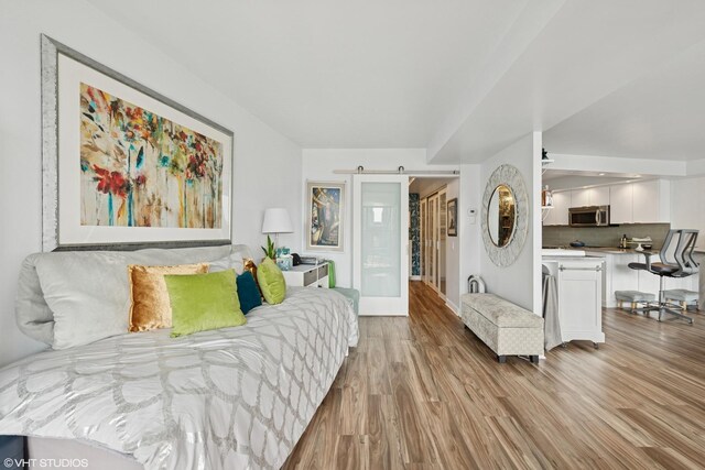 bedroom featuring a barn door and light wood-type flooring