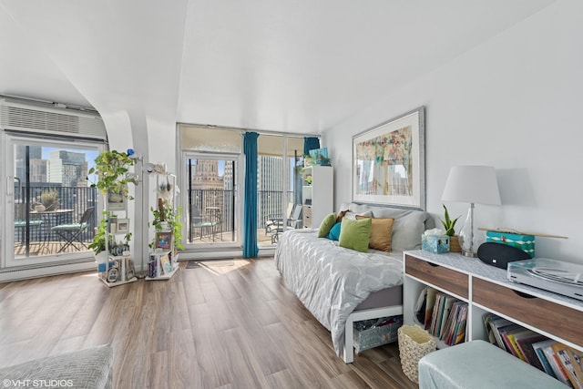 bedroom featuring access to outside, wood finished floors, and a baseboard radiator