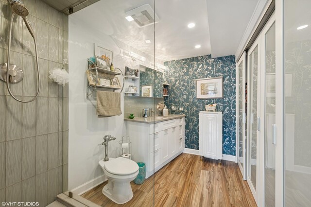 bathroom featuring wood finished floors, vanity, toilet, baseboards, and recessed lighting