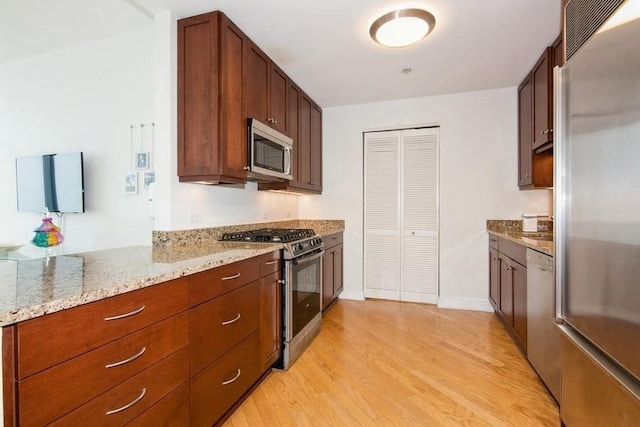 kitchen with light stone countertops, light wood-style flooring, baseboards, and appliances with stainless steel finishes