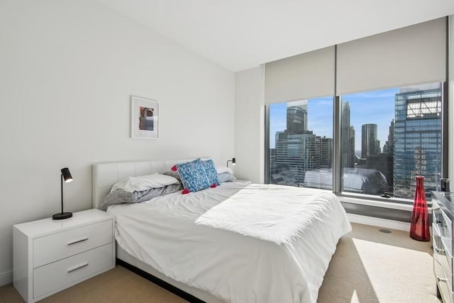 bedroom featuring light colored carpet and a city view