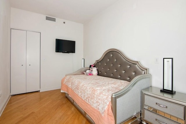 bedroom featuring a closet, visible vents, wood finished floors, and baseboards