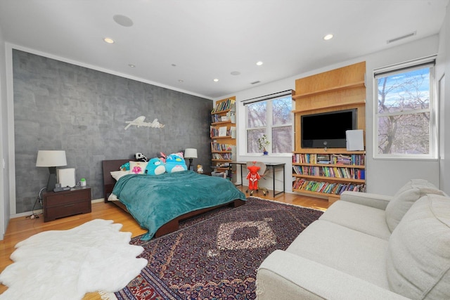 bedroom with wood finished floors, wallpapered walls, visible vents, an accent wall, and recessed lighting