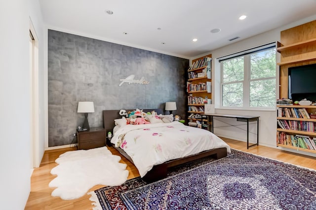 bedroom featuring recessed lighting, wood finished floors, baseboards, and an accent wall