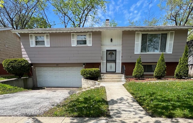 split foyer home featuring a garage, asphalt driveway, and brick siding