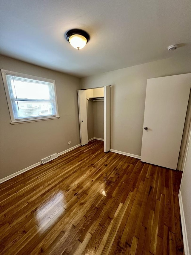unfurnished bedroom featuring wood finished floors, a closet, and baseboards
