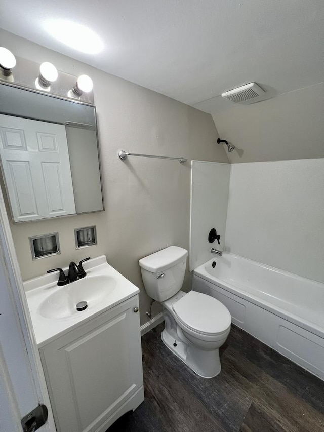 full bath with toilet, vanity, wood finished floors, washtub / shower combination, and lofted ceiling