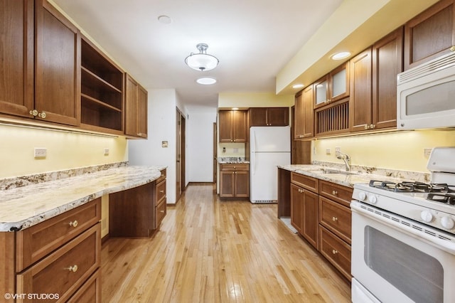 kitchen featuring glass insert cabinets, a sink, open shelves, white appliances, and light wood-style floors
