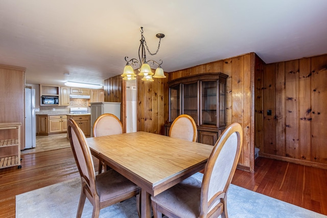 dining area featuring an inviting chandelier, light wood-style floors, and wood walls