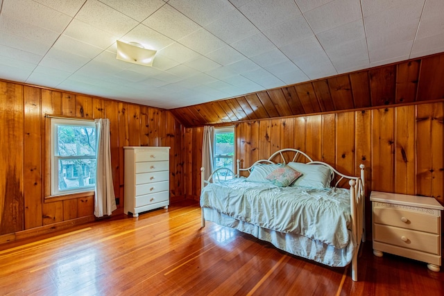 bedroom with multiple windows, vaulted ceiling, and wooden walls