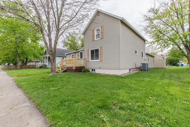 view of side of property featuring central air condition unit, a wooden deck, and a lawn