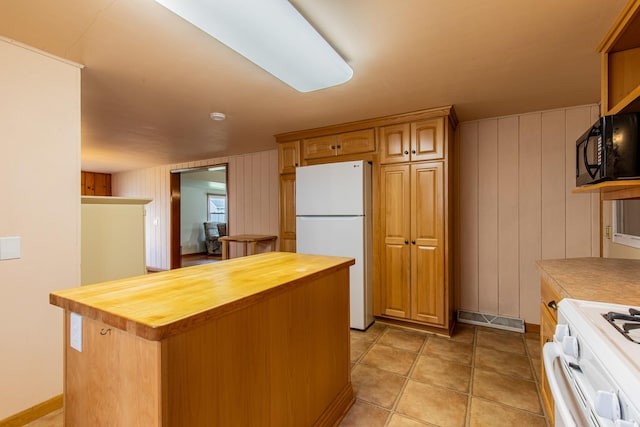 kitchen featuring baseboards, white appliances, butcher block counters, and a kitchen island